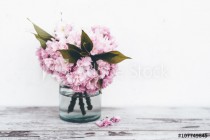 Branches of fruit tree in pink blossoms in glass vase on vintage wooden table with white background Naklejkomania - zdjecie 1 - miniatura