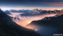Mountains in fog at beautiful night in autumn in Dolomites, Italy. Landscape with alpine mountain valley, low clouds, forest, colorful sky with stars, city illumination at dusk. Aerial. Passo Giau Naklejkomania - zdjecie 1 - miniatura
