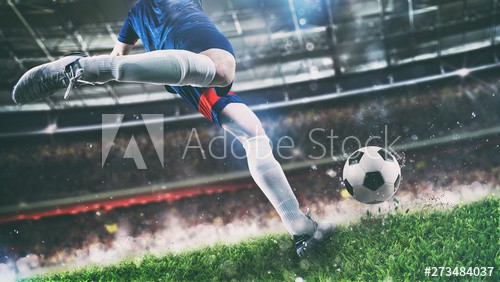 Football scene at night match with player kicking the ball with power