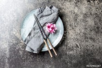 Chopsticks and sakura flowers on gray plate, stone background. Japanese food concept. Top view, copy space. Naklejkomania - zdjecie 1 - miniatura