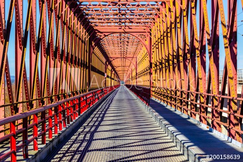 Red iron bridge crossing a river with roadway. - zdjęcie 1